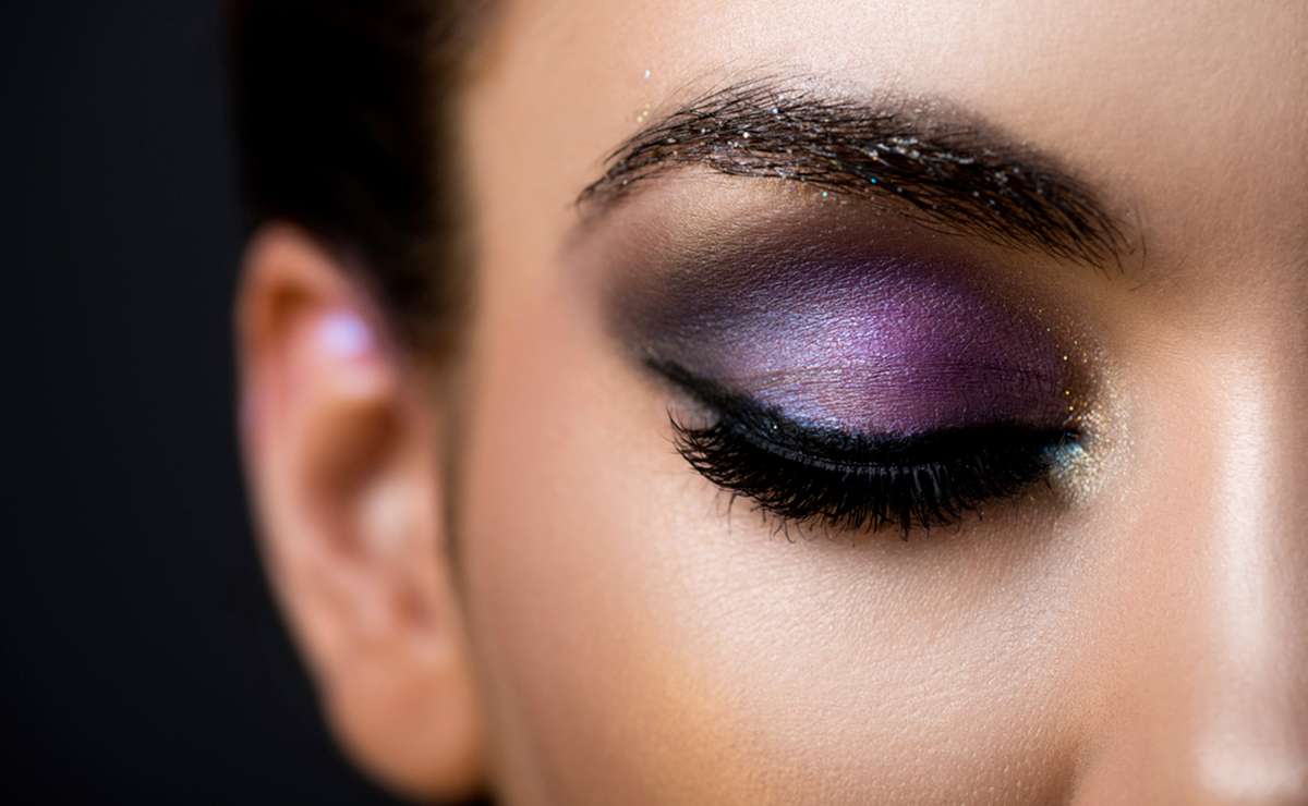 Consigli make-up occhi: trucco elegante con ombretto viola sfumato, accenti dorati e eyeliner nero per un look glamour da sera.